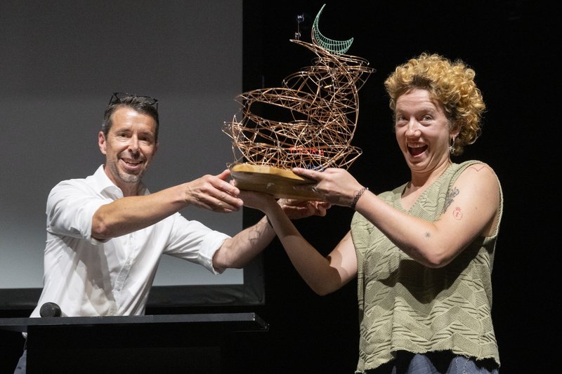 Georg Matter, Leiter der Abteilung Kultur des Kantons Aargau, überreicht Lotta Lechtenberg vom Kollektiv Panne Fatale die «Grünschnabel»-Trophäe, gestaltet vom Wettinger Künstler Alain Schartner.